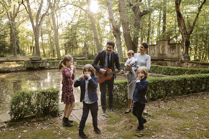 Familia reunida junto al estanque con guitarra y armónicas en una finca familiar al atardecer