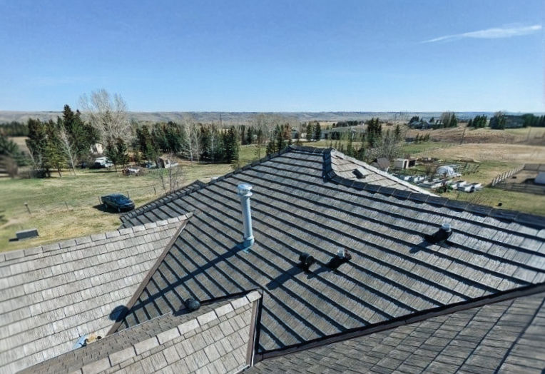 Shingled roof of a house against a rural backdrop