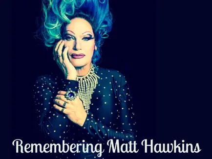 Divine Miss M in a blue wig and dress. Her hand is against one side of her face. Below the photo is reads: Remembering Matt Hawkins the Divine Miss M