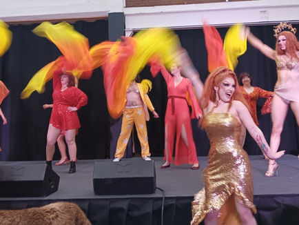 House of Allure dancing with their dance glass, they all wear orange, yellow, red and gold and wave flags of the same colours.