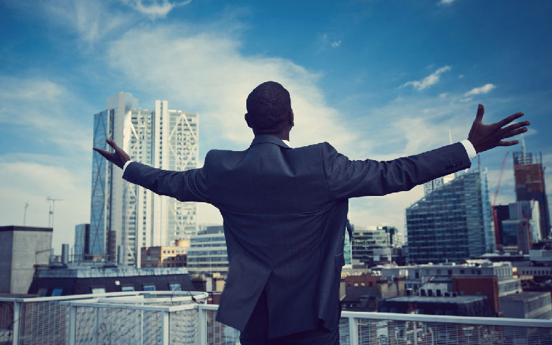 Man in suit with arms outstretched overlooking city