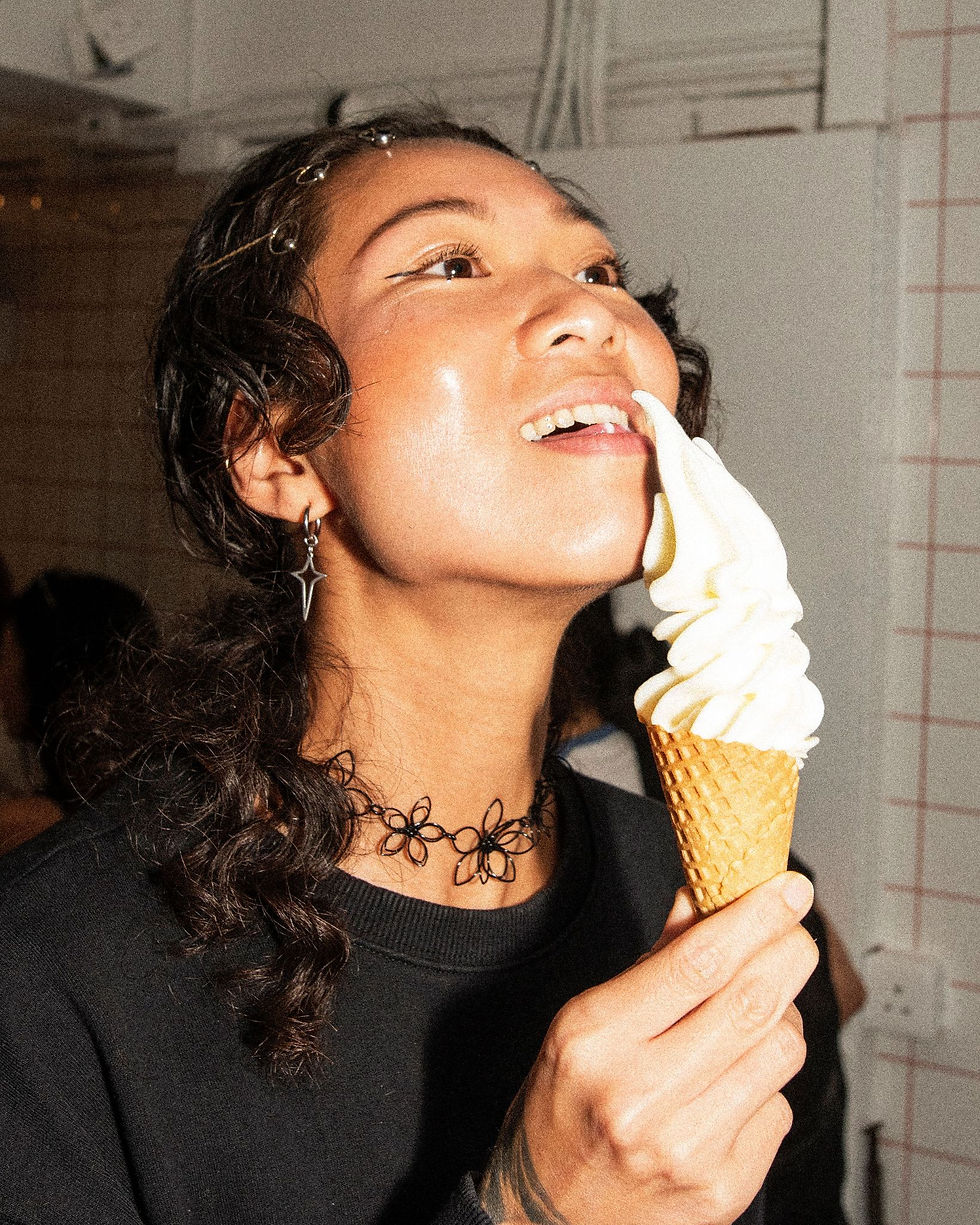 A girl with a soft serve ice cream cone close to her nose