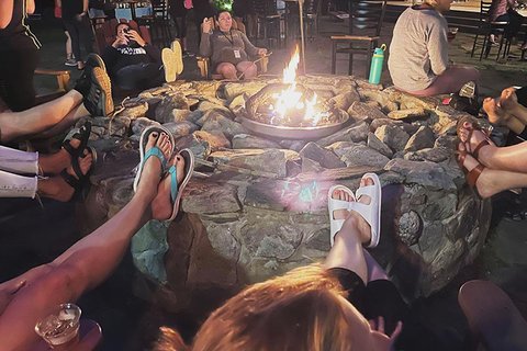 Group of people sitting around a campfire at night relaxing together