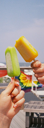 Colorful popsicles held up near a Pride flag in Fire Island Pines.