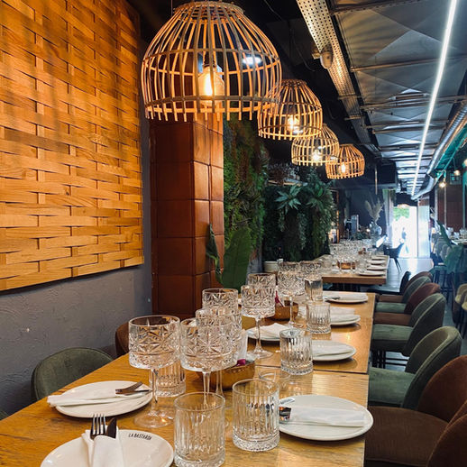 Interior de restaurante con mesas puestas y lámparas de mimbre. Restaurante Sin Gluten Sevilla.