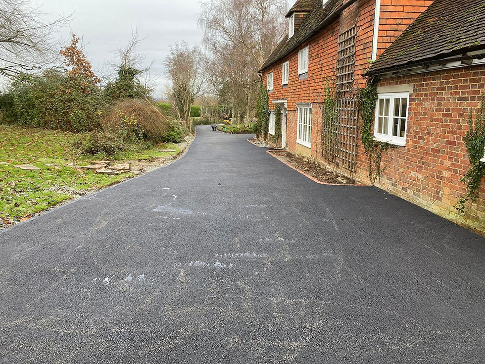 Newly paved tarmac driveway beside a red brick English country cottage
