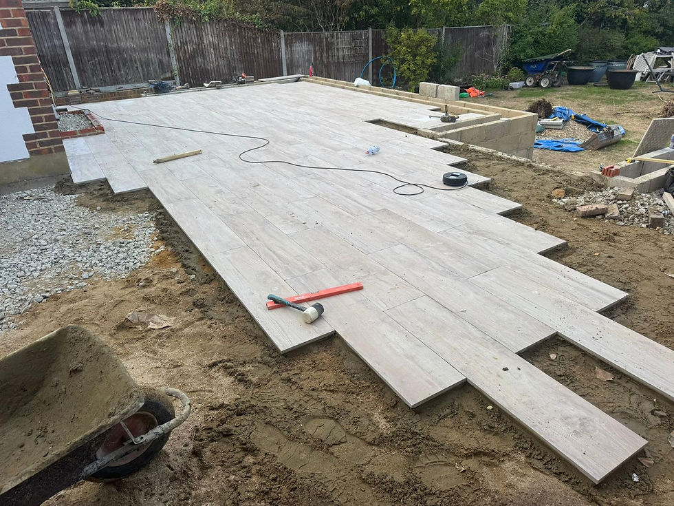 Large wood-effect paving slabs being laid in a garden under construction
