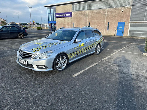 Silver estate taxi parked in a commercial car park