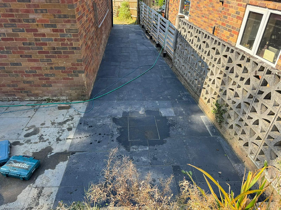 Narrow alleyway with dark slate paving, hose, and Makita toolbox beside brick walls