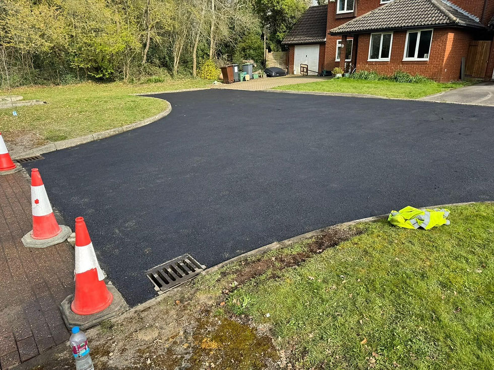 Freshly laid tarmac driveway outside a brick house with traffic cones