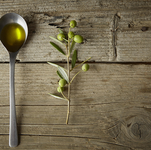 Huile d'olive vierge première pression à froid, cuillère et branche d'olivier.