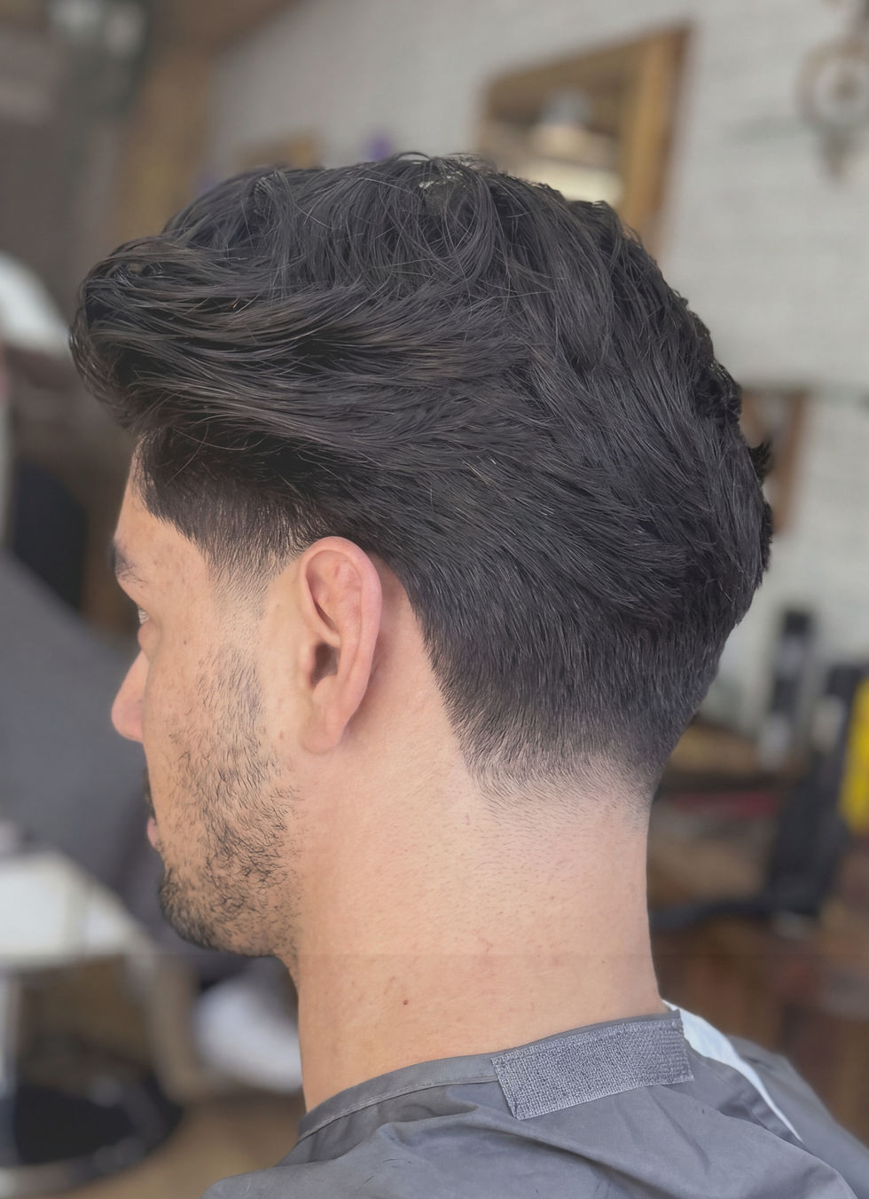 Man with dark, wavy hair and a modern fade haircut