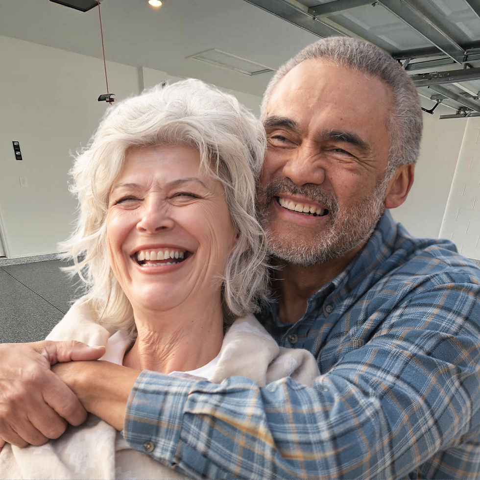 Elderly couple laughing, embracing warmly in a bright room with a partially open garage door. The man wears a blue plaid shirt, adding a joyful mood.