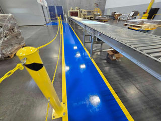 Aisleway in a production facility featuring a blue epoxy sidewalk with vibrant yellow markings.