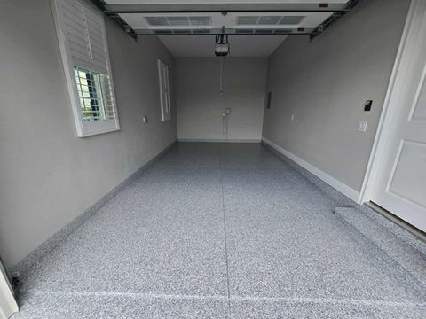 Garage space with a professionally installed Domino epoxy floor featuring a bold monochrome flake pattern that combines industrial strength with modern aesthetics.