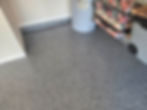 Gray speckled floor, blue water heater, and stacked colorful suitcases beside gray storage box on wheels in a garage corner.