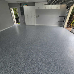 Wide view of a clean, finished garage floor coated in Lagoon Blue epoxy with soft blue, light gray, and white flake details.