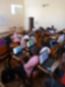 18 students picture in a classroom sitting at their desks, many are on computers with aerial imagery showing.