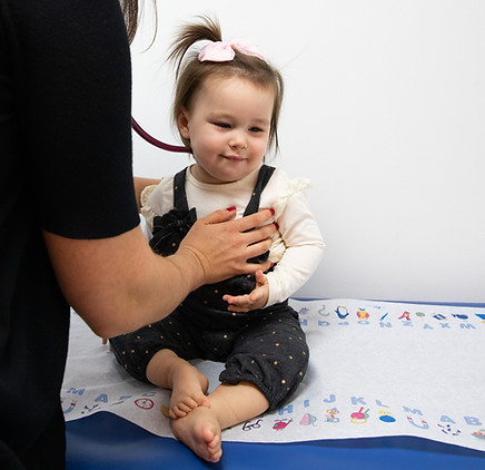 Cute baby smiles as doctor listens to her heartbeat
