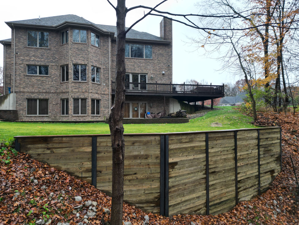 a large brick house with a large deck behind a wooden piling wall