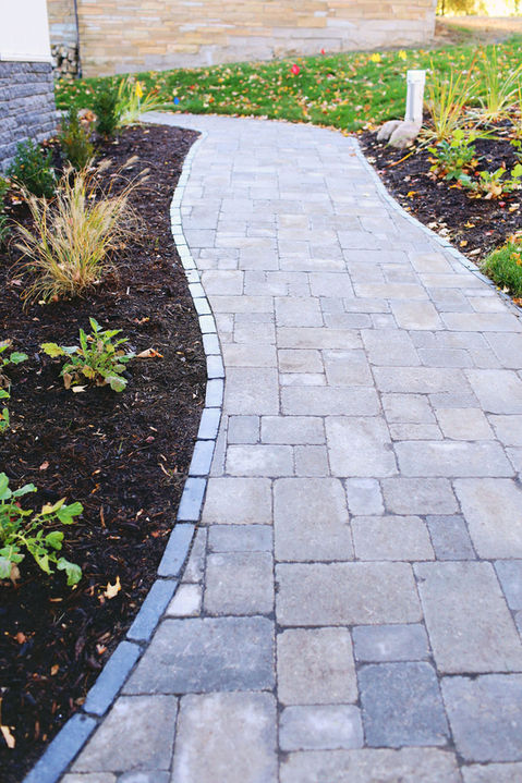 a brick walkway going through a lush green garden