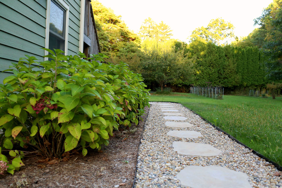 a stone walkway leading to a green house