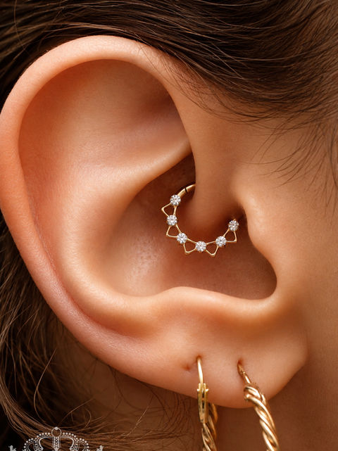 Gepierctes Ohr mit einem Ring in Gold mit Glitzersteinen. Auch genannt Daithpiercing.