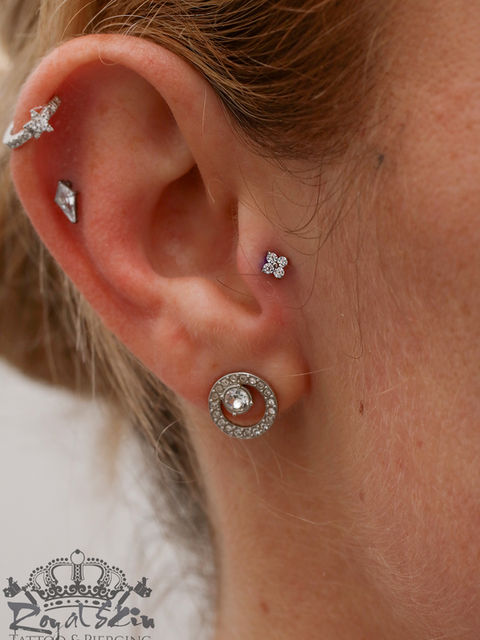 Ohrpiercing mit einem Goldstecker und Kristallen.