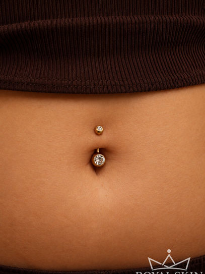 Ein weibliches Bauchnabel mit einem Goldstecker als Piercing.