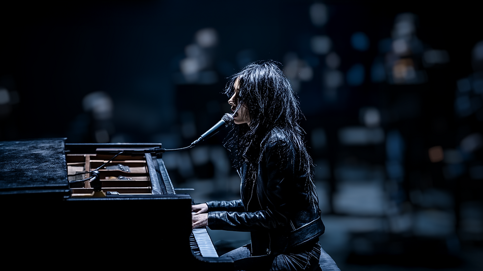 Isla, in a leather jacket, sings and plays the piano on a dimly lit stage, evoking an intense, moody atmosphere with blurred figures. Isla performs an emotional set drawn from her career, Songs such as "What you don't see", "Raise the fourth (A drop from the fourth)" and "Memory under water". PixelStortion, Ethel Ryker, Dominic Ryker.