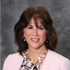 Smiling woman in pink blazer and pearl necklace