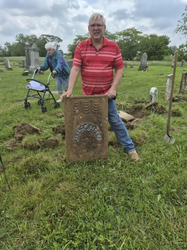 Man holding restored headstone, cemetery