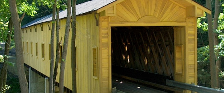 Yellow wooden covered bridge in a lush green forest