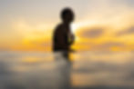 Surfer sitting on a surfboard in the sea at sunset
