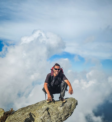 Pedro Cruz, coordinador de Pasaporte Pirata subido en una piedra con un mar de nubes de fondo