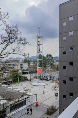 Fotografie des Wahrzeichens der Siedlung Tscharnergut, der Glockenturm auf dem Dorfplatz, in Berns Westen von Susanne Goldschmid Fotografin aus Bern