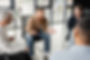 Cheerful man with alcohol addiction talking to interracial group in rehab center.jpg
