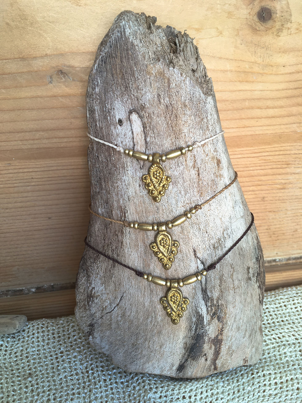 Three minimal brass macrame necklaces in light, mid-tone, and dark brown displayed on driftwood and natural textures