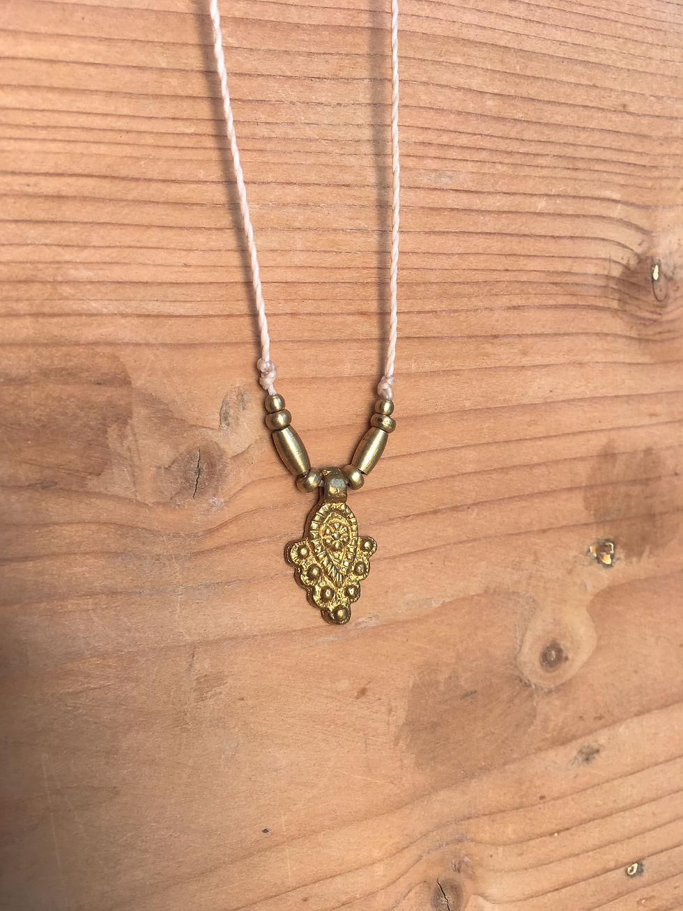 Thumbnail: Light toned minimal necklace shown hanging against a wooden backdrop