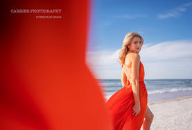 High school senior in a red dress posing on the beach during a senior photography session in Clearwater, Florida