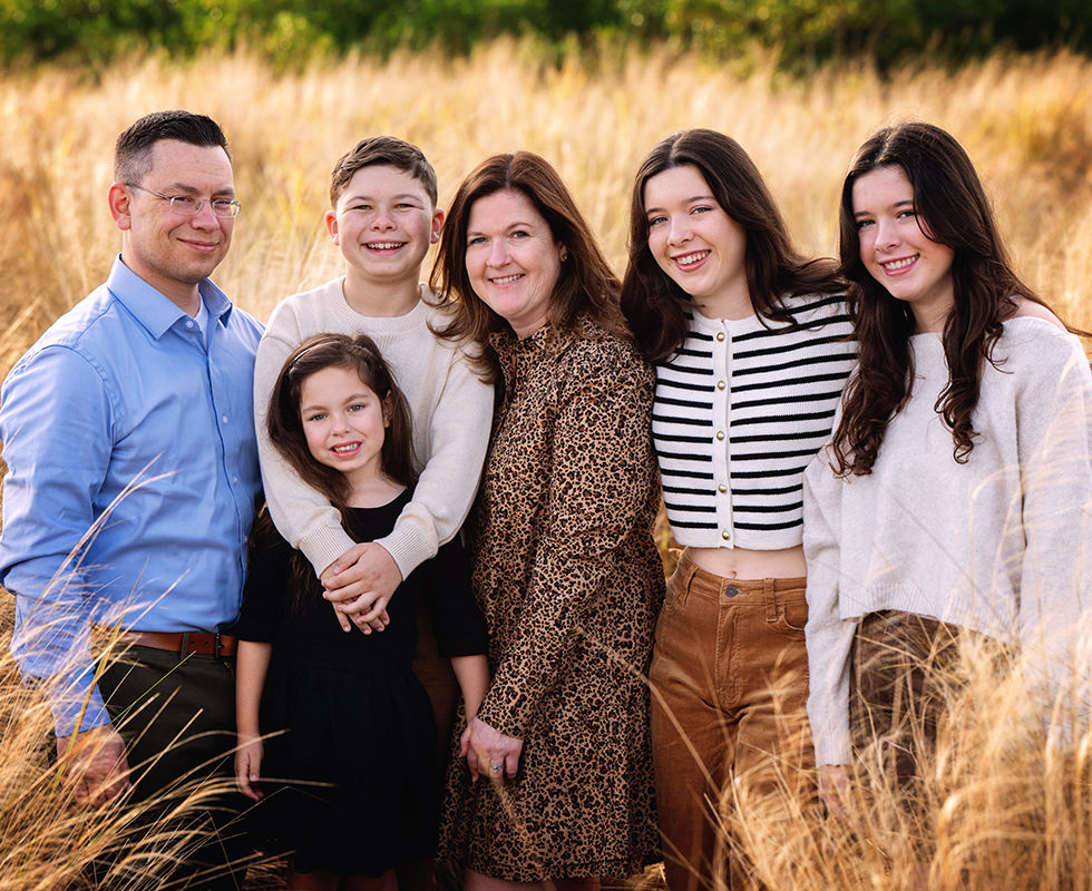 Large family smiling together in a sunlit field during an outdoor family photo session in Tampa, Florida