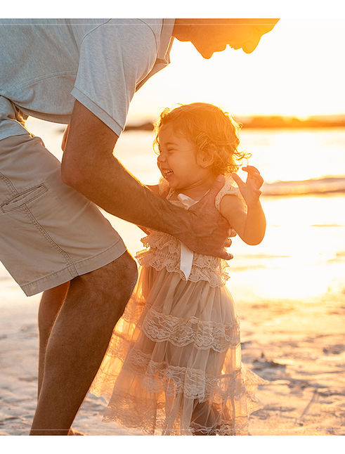 Father playing with his young daughter at sunset during a Honeymoon Island family beach photography session