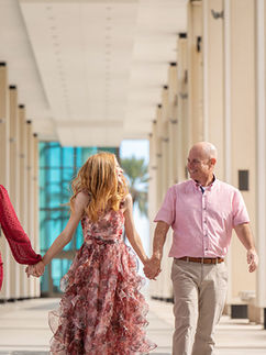 Parents walking hand in hand with their daughter during a family portrait session in St Petersburg, Florida