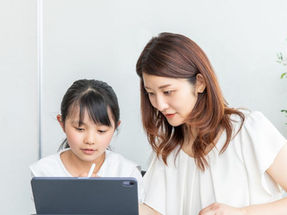 タブレットで宿題を確認する母親と子ども
