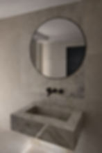 Modern bespoke washbasin with black faucet and round mirror