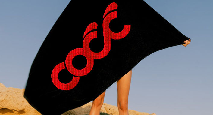 Large red COCC logo embroidered on a black towel from the merchandise collection.