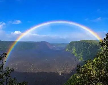 Rainbow arching over Kīlauea crater and the surrounding native forest in Hawaiʻi Volcanoes National Park