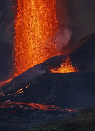 towering lava fountain erupts from the Kīlauea volcano, shooting bright orange and red molten rock high into the dark sky