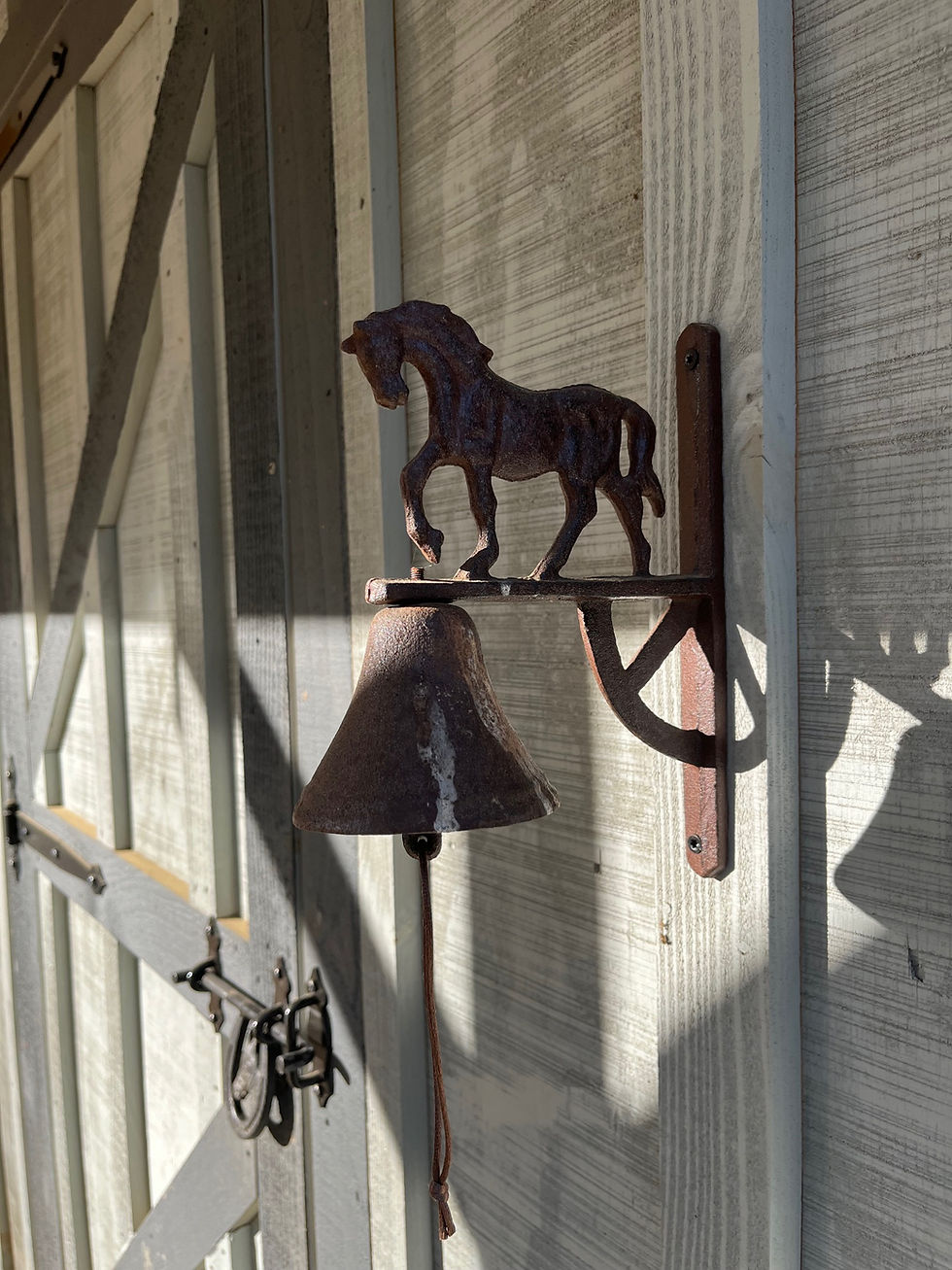 Metal bell with horse silhouette on barn door