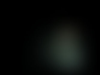 A figure curled small in a pool of light on a vast dark stage.